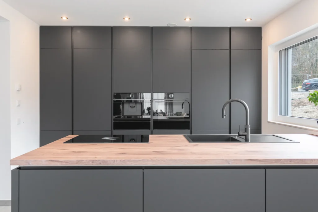 Elegante grifflose Küche mit mattschwarzen Fronten und robuster Holzoptik-Arbeitsplatte aus Laminat für modernes Küchendesign.