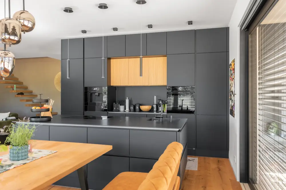 Die Kombination aus schwarzer Kochinsel und Holztisch bringt Wärme in das moderne Design.