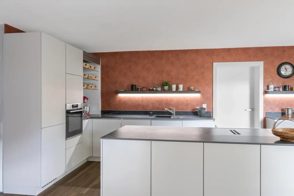 Gesamte Ansicht der modernen U-Kueche mit Nobilia Fronten, Kochinsel und dunkler Marazzi