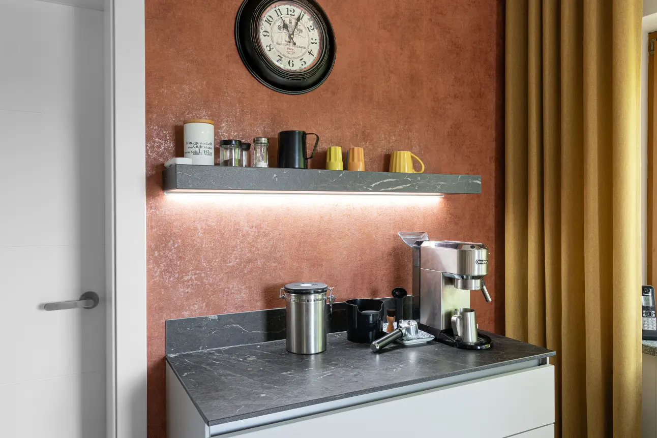 Kaffeestation mit Marmoroptik-Arbeitsplatte, offenes Regal und stimmige Wandfarbe.