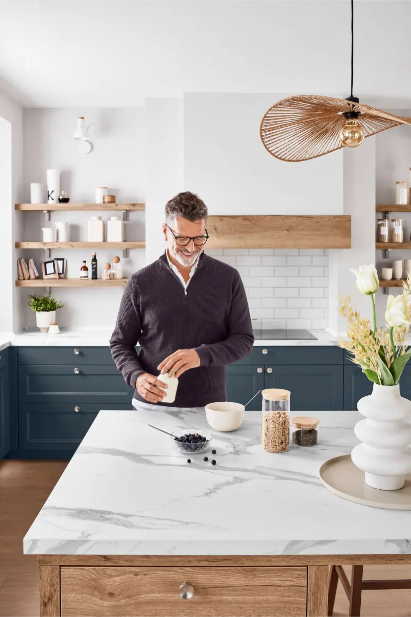 Mann bereitet Frühstück auf Kücheninsel mit Marmoroptik