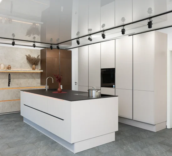 Stilvolle Küche mit hellen matten Fronten und kontrastierender dunkler Arbeitsplatte.