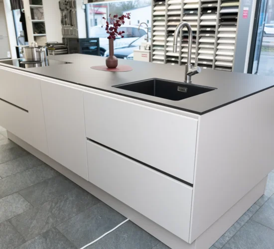 Küchendesign mit dunkler Arbeitsplatte und stilvoller LED-Griffmuldenbeleuchtung.