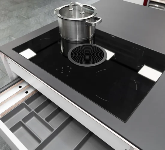 Induktionskochfeld mit integriertem Dunstabzug und funktionalen Küchenschubladen.