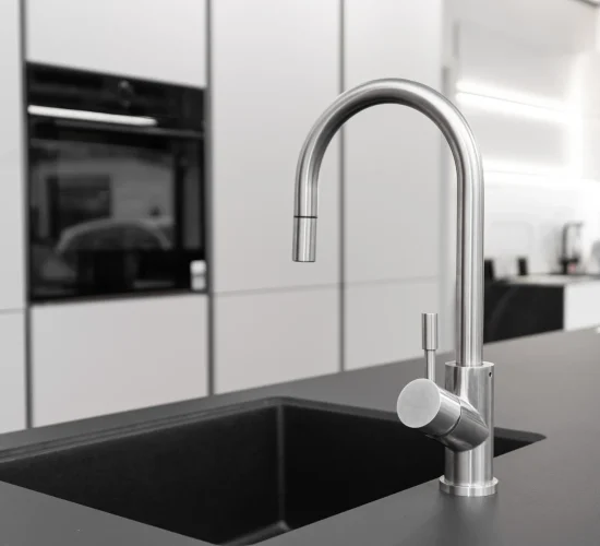 küche mit Edelstahlarmatur und schwarzem Spülbecken in dunkler Arbeitsplatte.