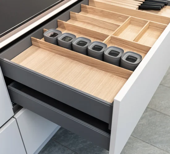 Intelligente Küchenschublade mit Holz-Besteckeinsatz und modernen Gewürzbehältern.